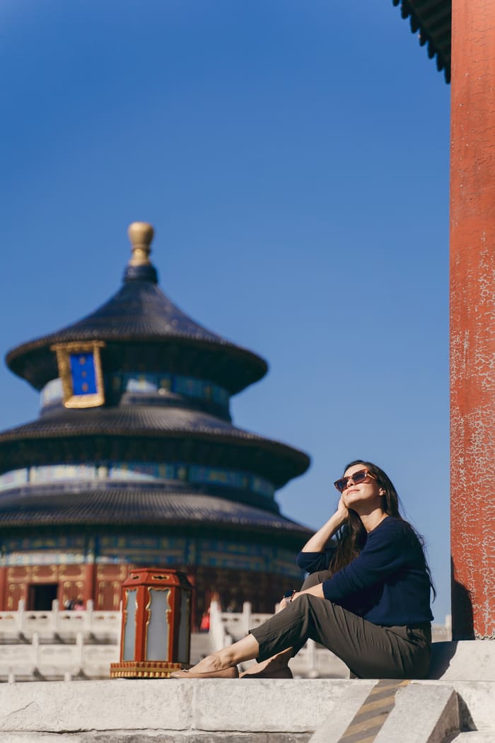 una mujer con lentes de sol sentada de fondo un templo chino