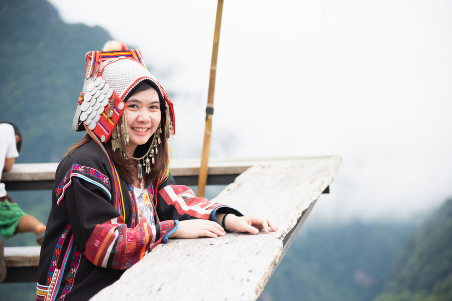 una mujer china apoyada en un barandal de un mirador y de fondo unas montañas con nieve