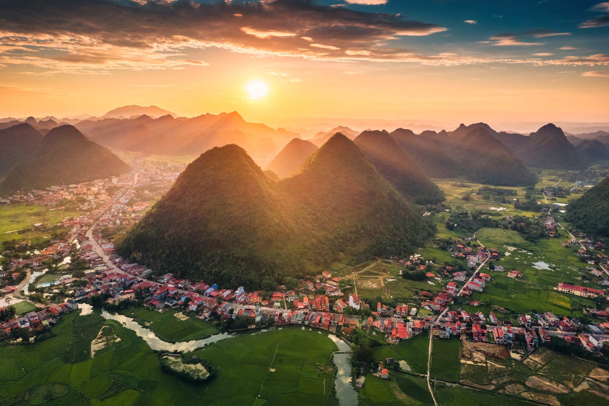 se logra ver una ciudad de fondo unas montañas con un hermoso atardecer de Yangsho