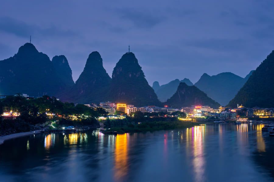 un lago a las orillas de una ciudad china y unas montañas de fondo